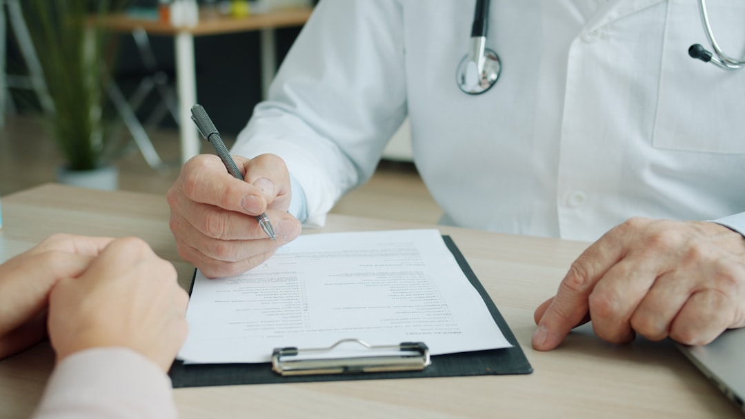 Nurse practitioner writing notes on a clipboard across the desk from a patient, the diagnostic reasoning weighted heaviest on the FNP exam