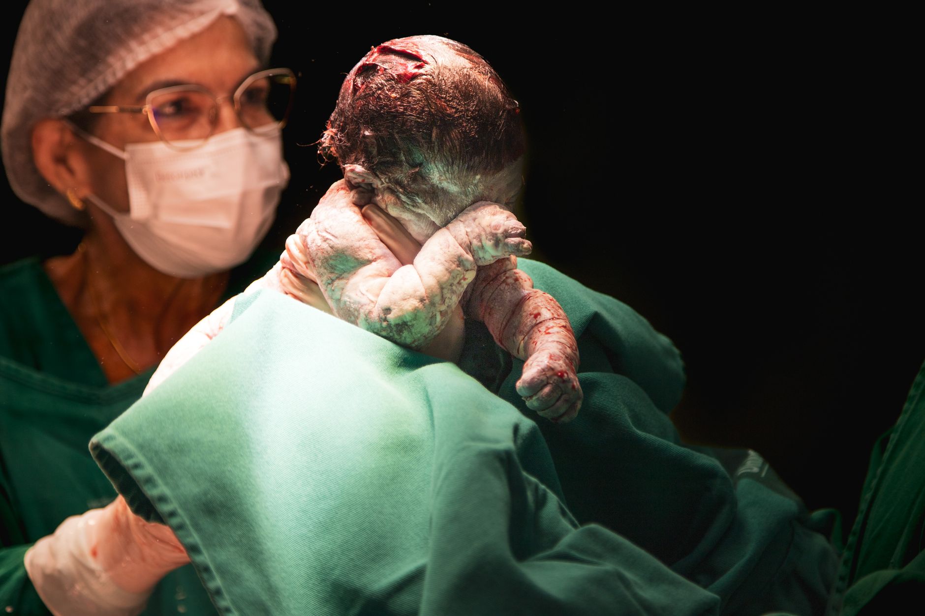 Midwife holding a newborn shortly after delivery in a hospital birthing room