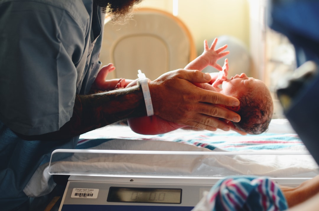 Clinician weighing a newborn on a scale during a postpartum newborn assessment