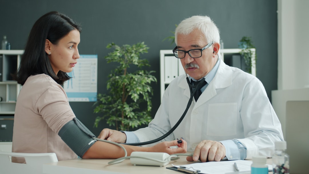 Clinician checking a patient's blood pressure with a stethoscope in an outpatient primary care clinic