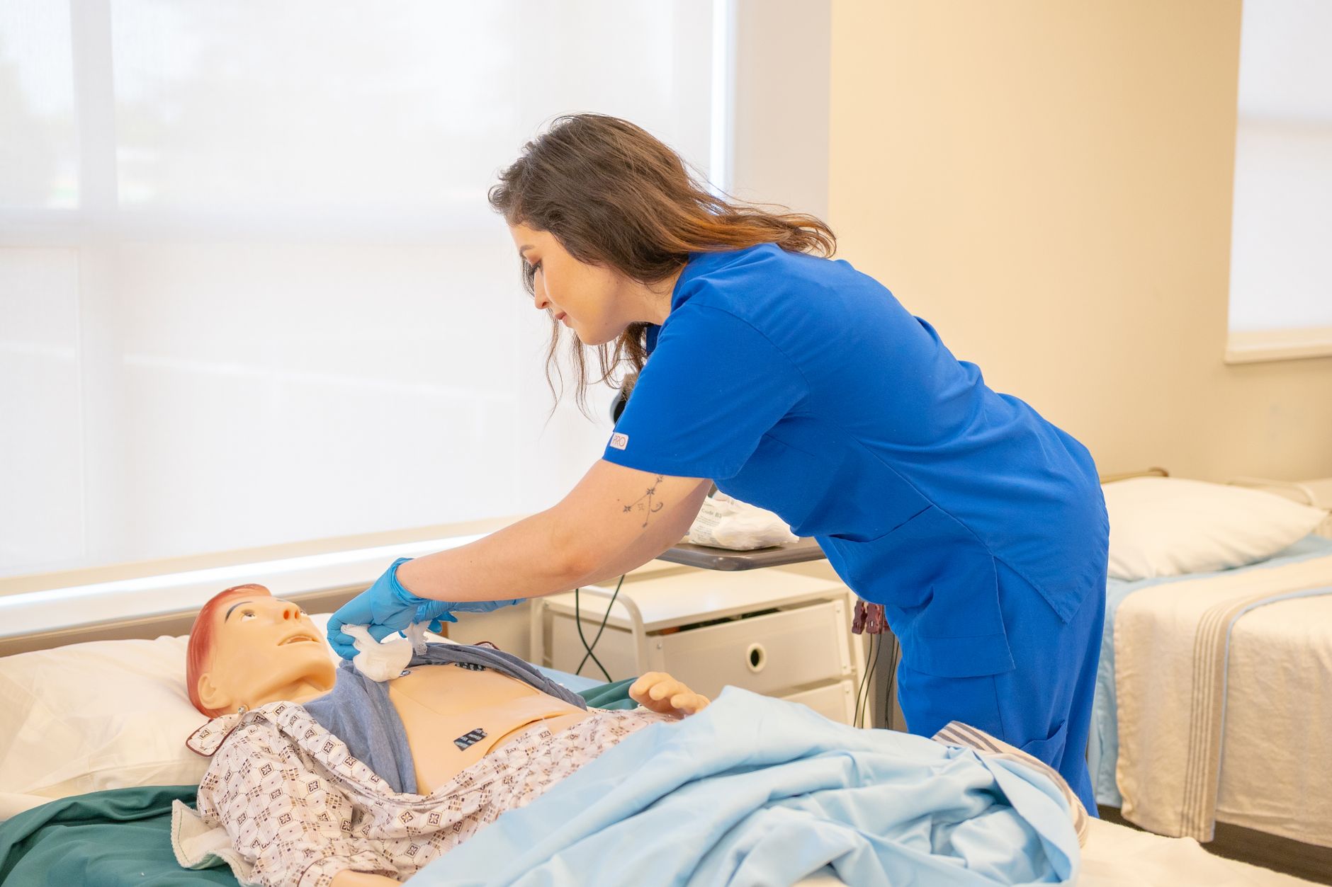 Nursing student practising a clinical skill on a training manikin during a program