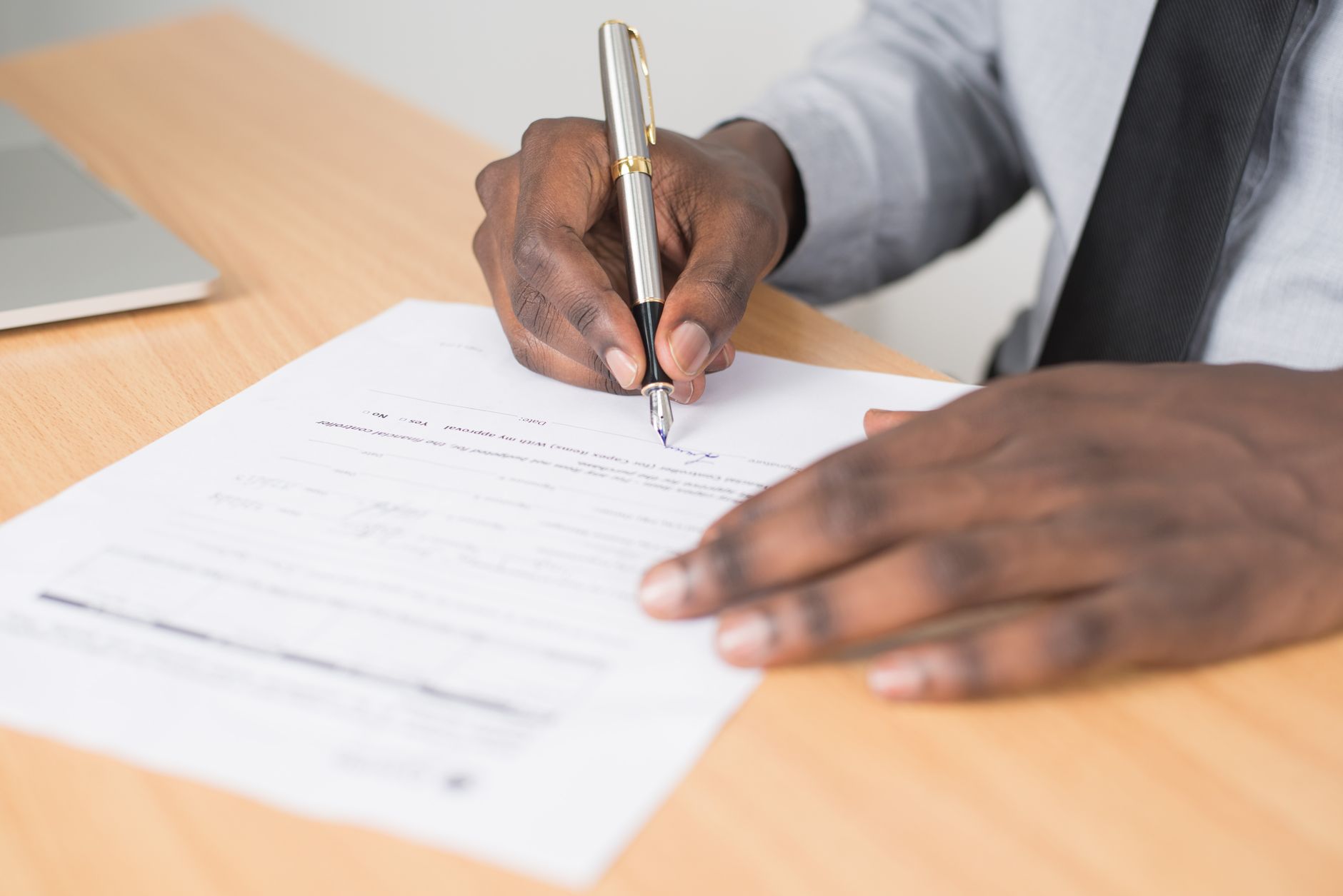 Person completing and signing an application document at a desk
