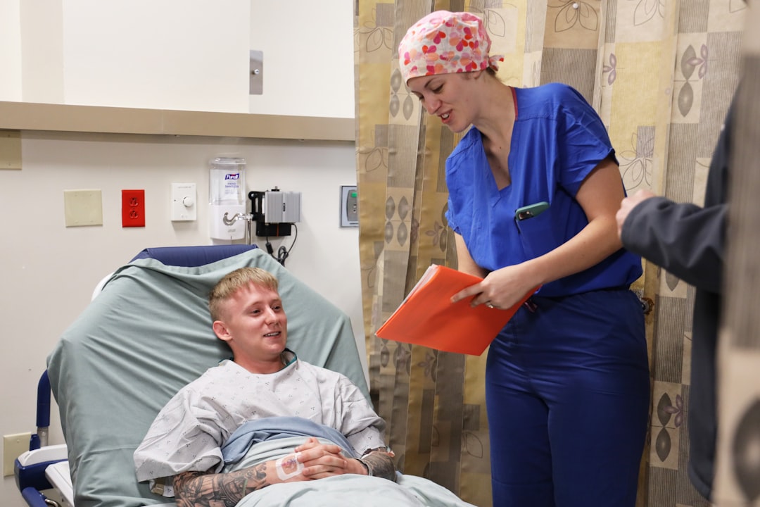 Nurse in scrubs talking with a patient at the bedside during a shift
