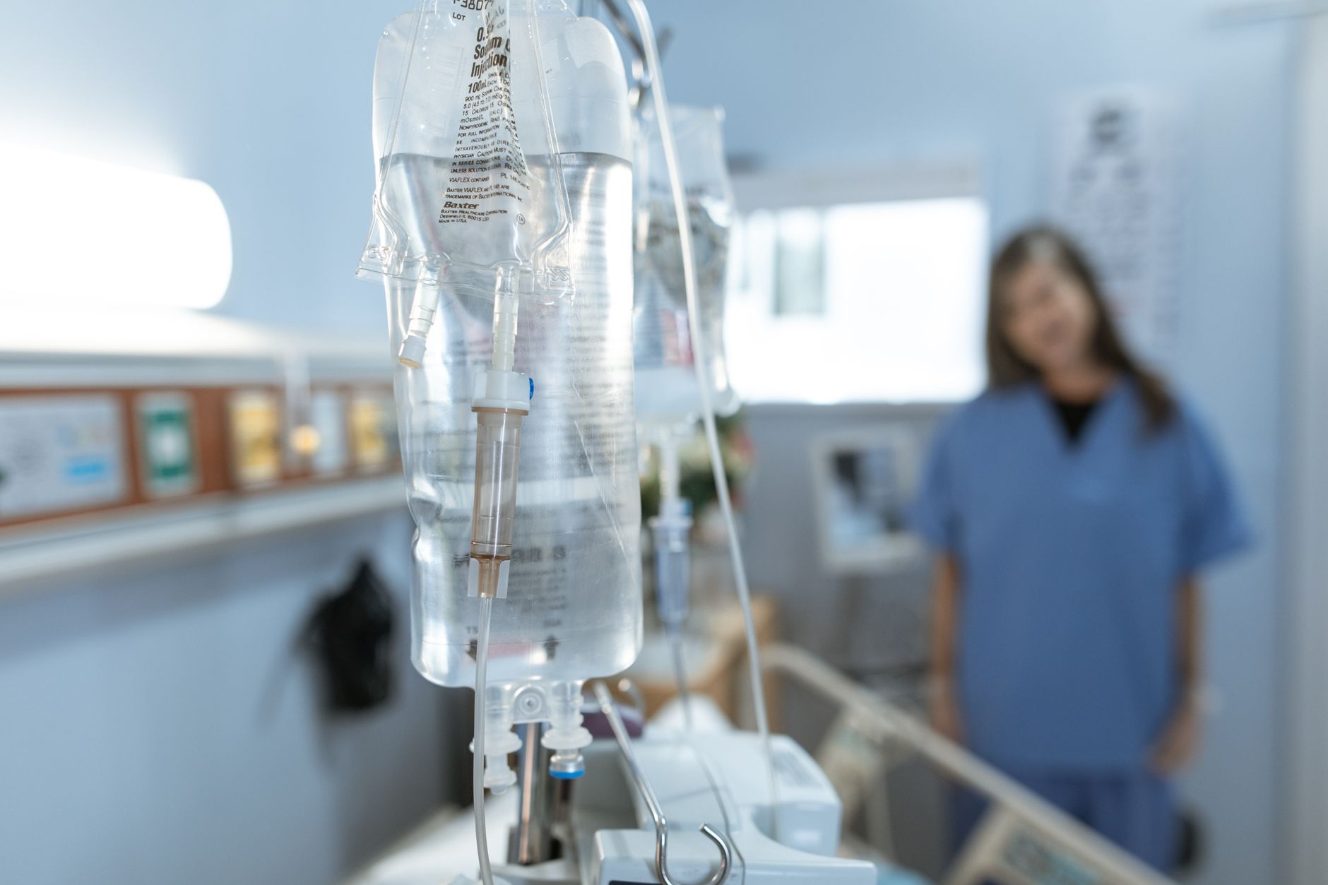 Saline infusion bag and giving set hanging beside a hospital bed, the fluids and medications an infusion nurse delivers and monitors