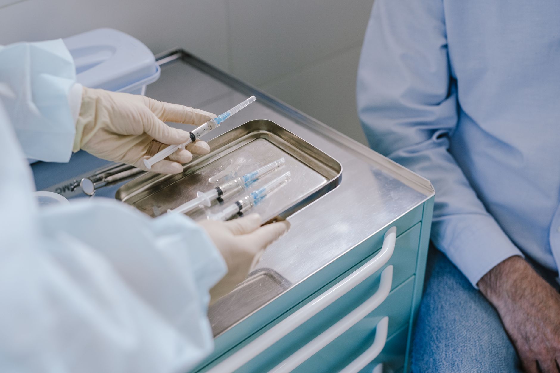 Gloved hands preparing syringes on a tray, a core practical nurse scope area