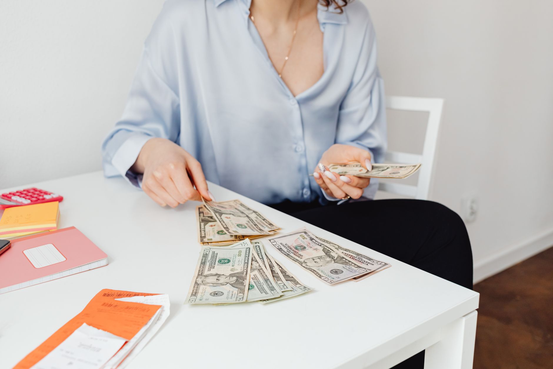 Counting US dollar bills at a desk, weighing LPN to BSN tuition against the BLS wage gap between LPN and registered nurse pay