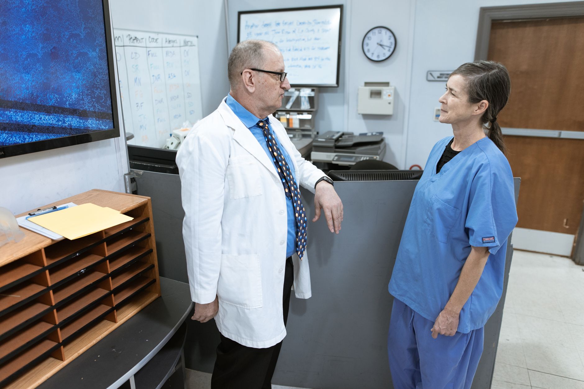 Physician and nurse conferring at a hospital workstation, the supervision relationship an LPN works under and an RN steps outside of