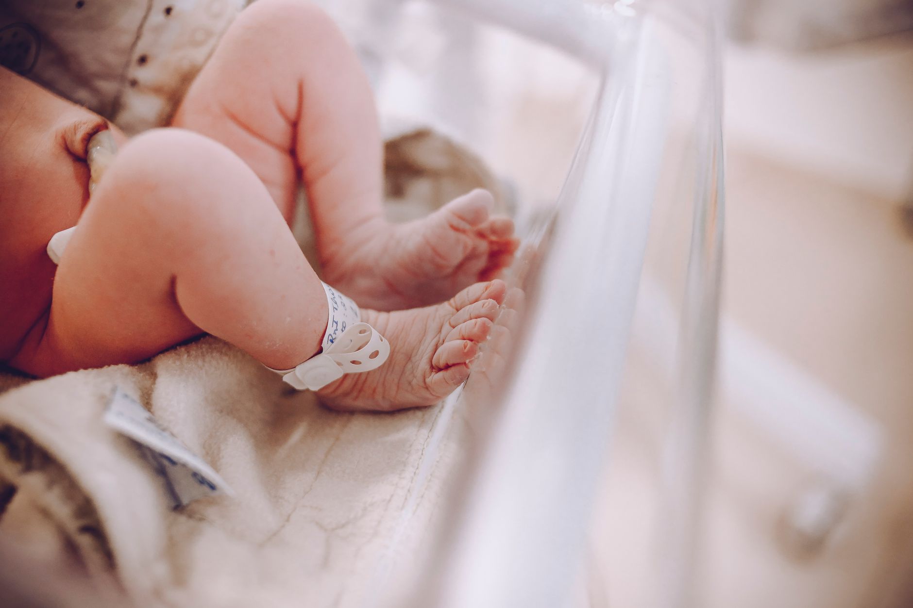 Newborn in a hospital bassinet wearing an identification ankle band