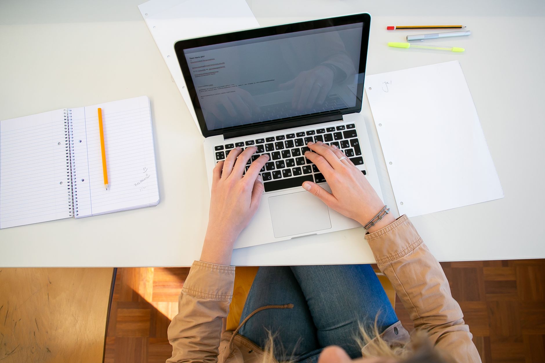 Overhead view of a candidate working at a laptop with notes, registering for the NCLEX with Pearson VUE