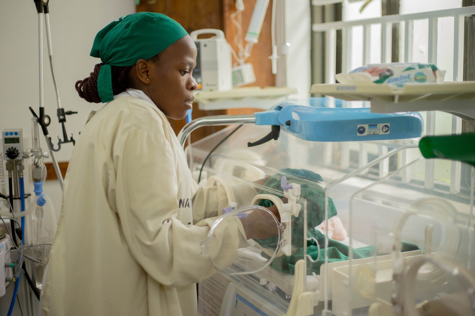 NICU nurse caring for a newborn in an incubator in a neonatal intensive care unit
