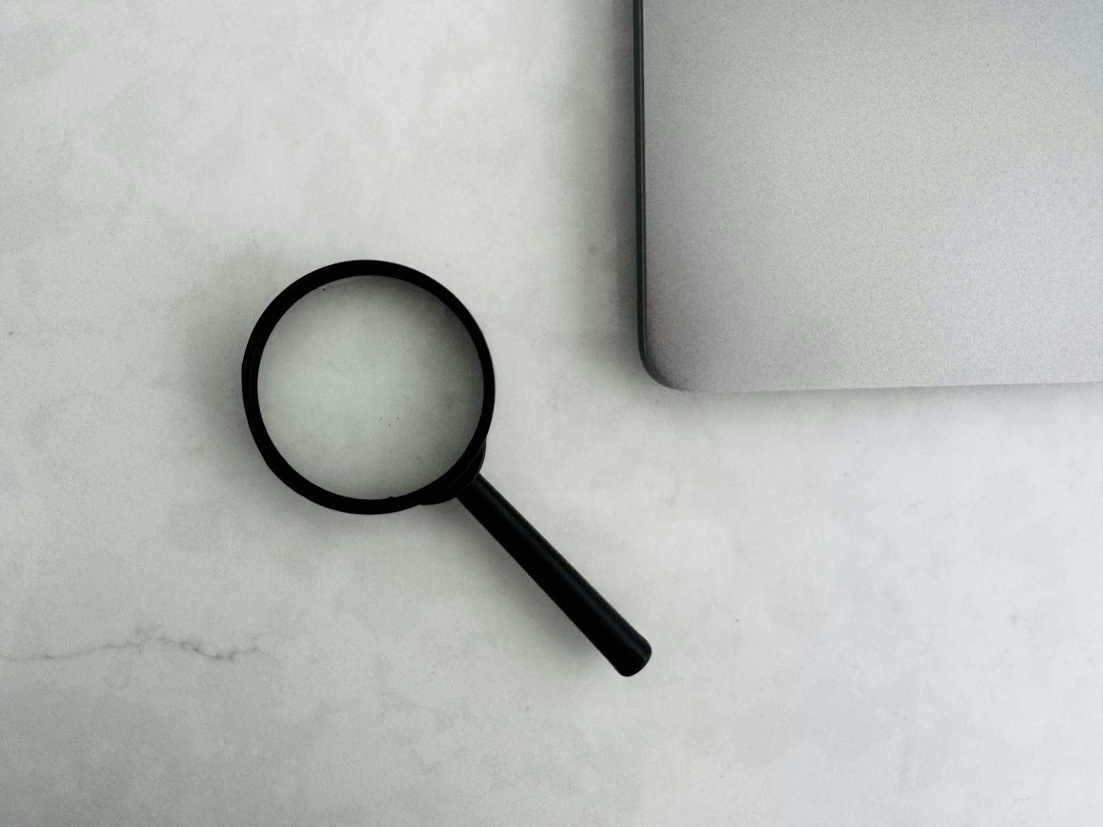 Magnifying glass beside a laptop, checking which certification exam a nurse practitioner program actually leads to before enrolling