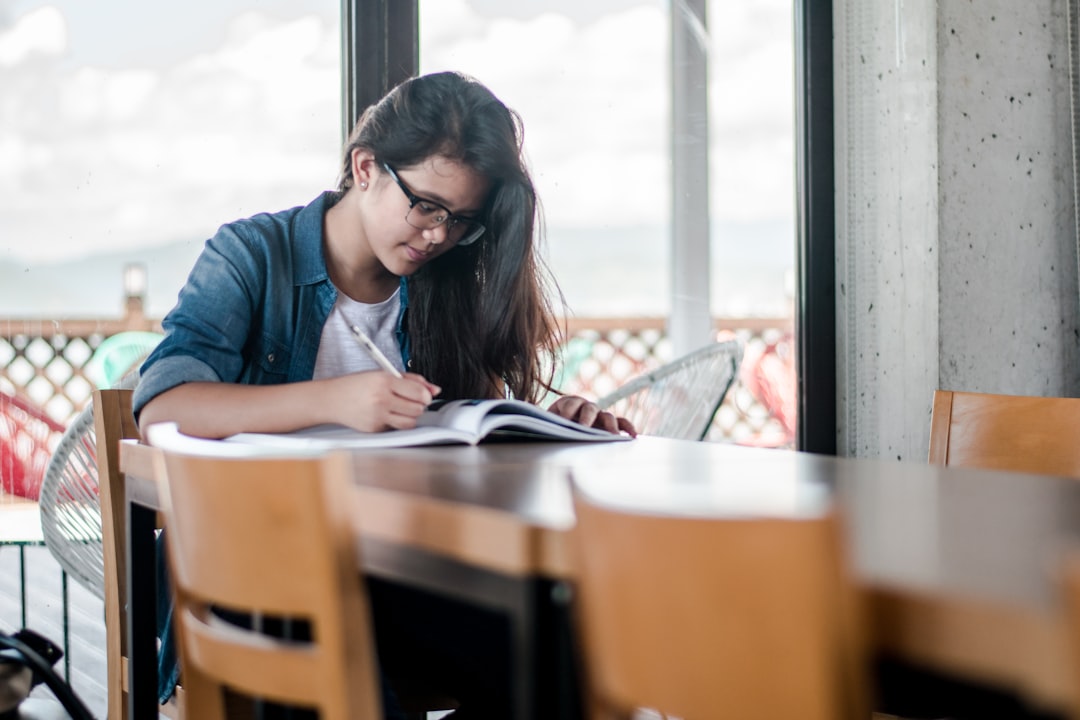 Nurse writing out assessment mnemonics while studying from a textbook