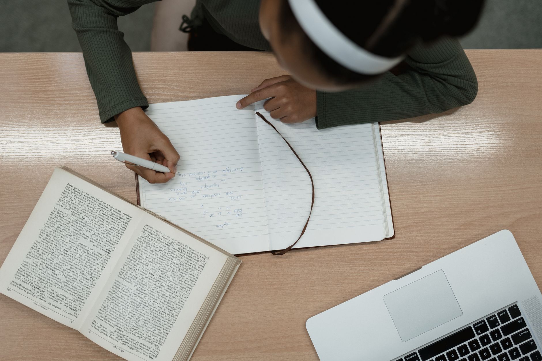 Student writing reflective notes in a notebook after reviewing answers
