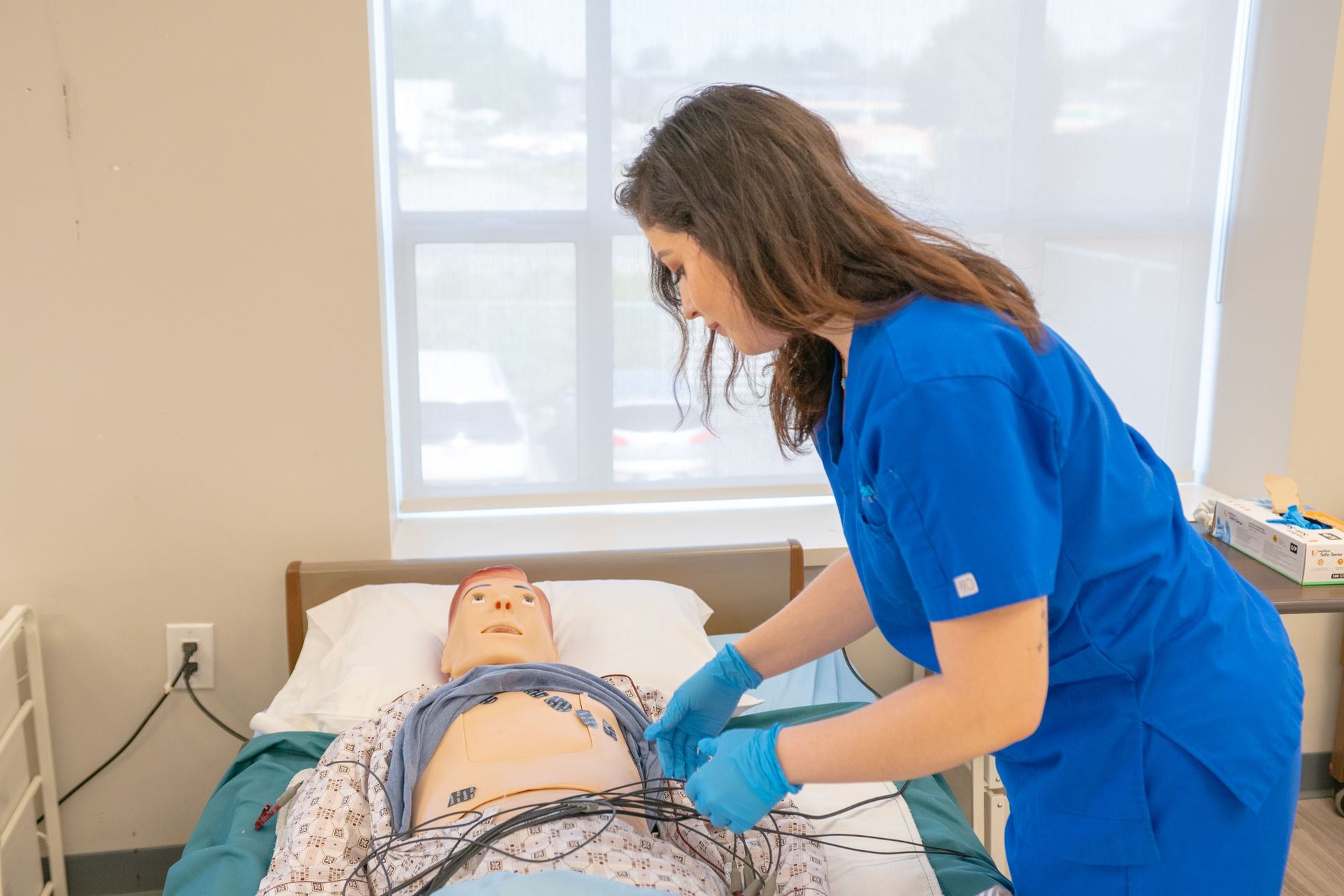 Nursing student practising a clinical skill on a manikin, the on-campus component no online program removes