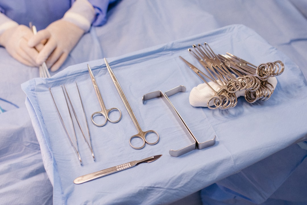 Sterile instrument tray laid out for surgery beside a gloved scrub nurse's hands