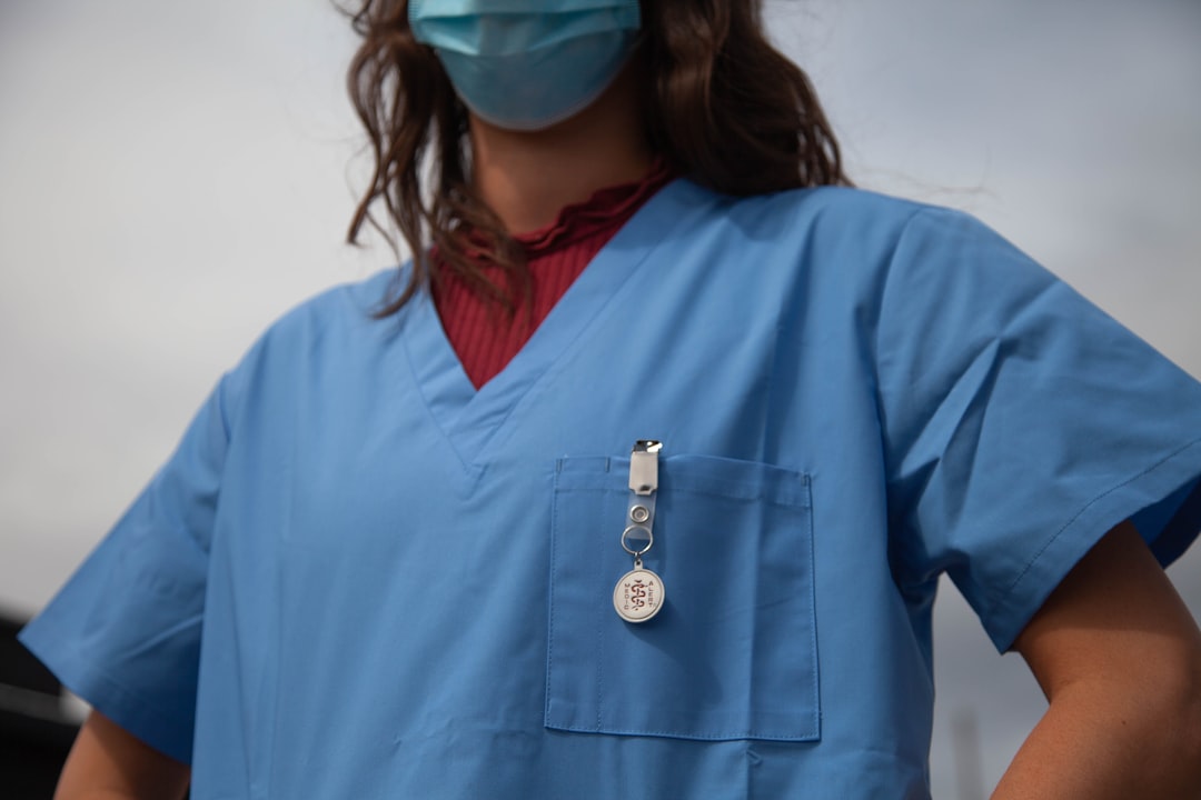 Perioperative nurse in surgical scrubs and mask wearing a hospital ID badge