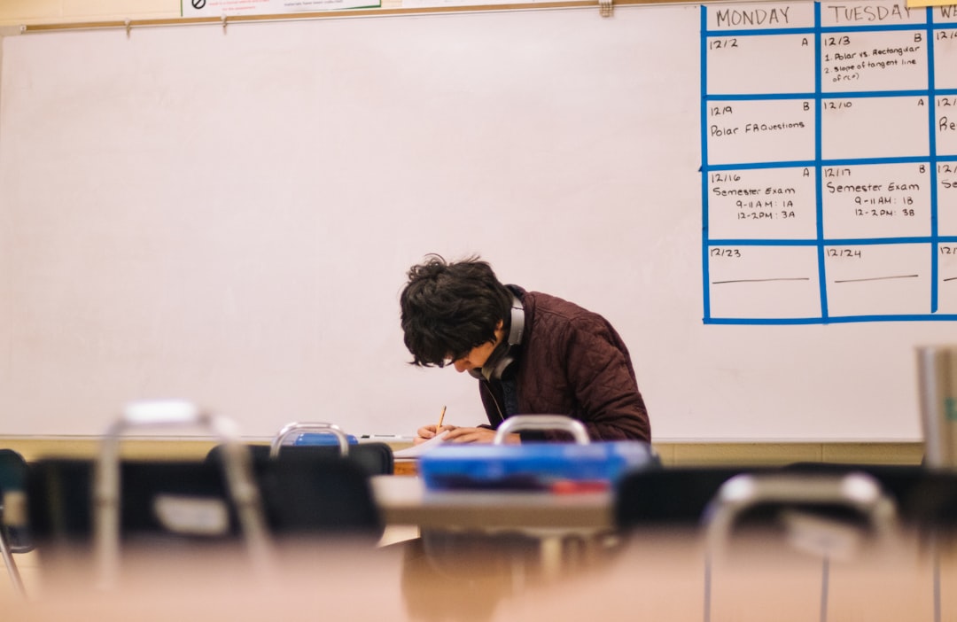 Student writing at a classroom desk practicing active recall for an exam
