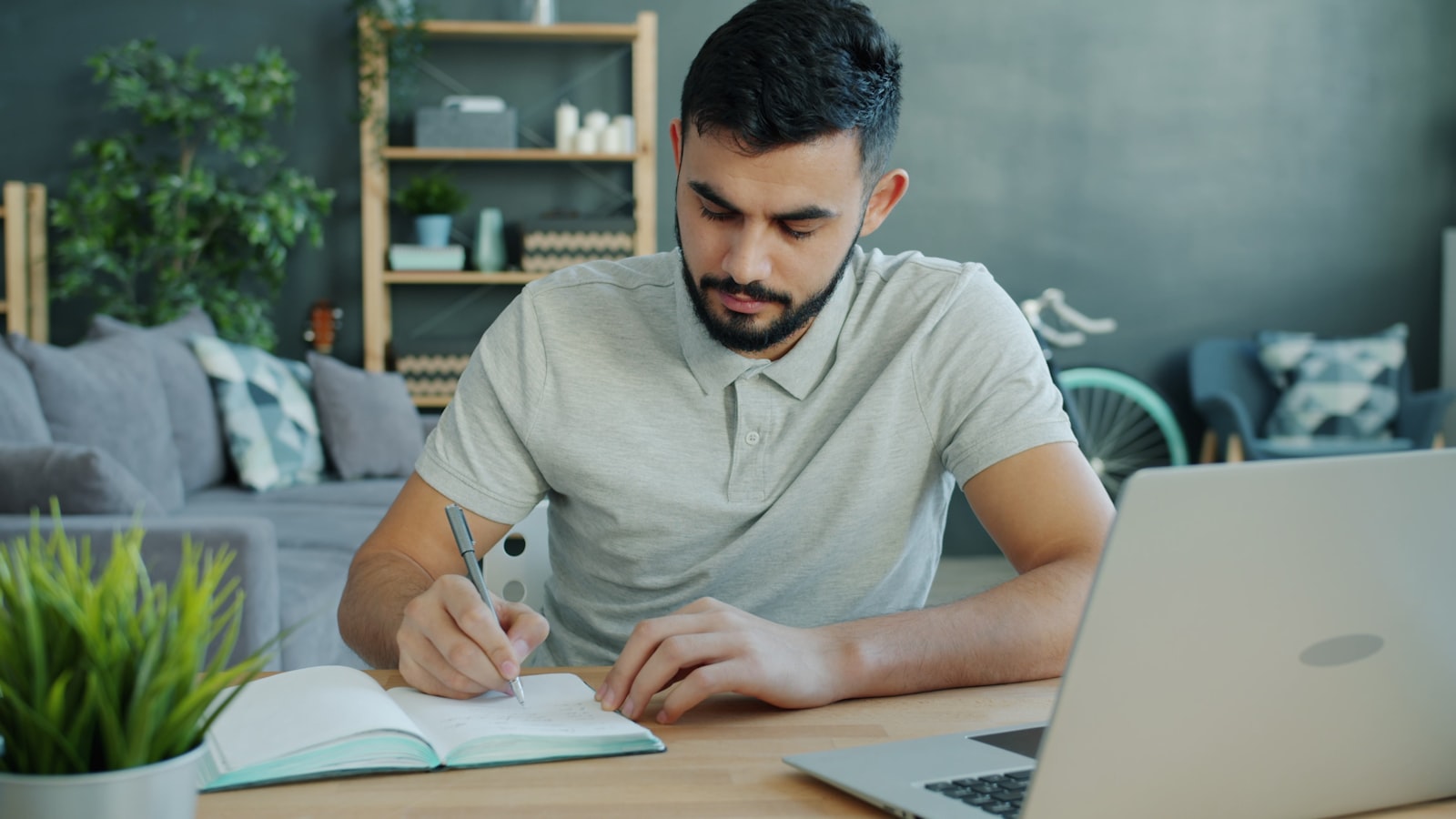 Student writing on blank paper beside a laptop, the single sheet of blank scratch paper permitted during the online TEAS