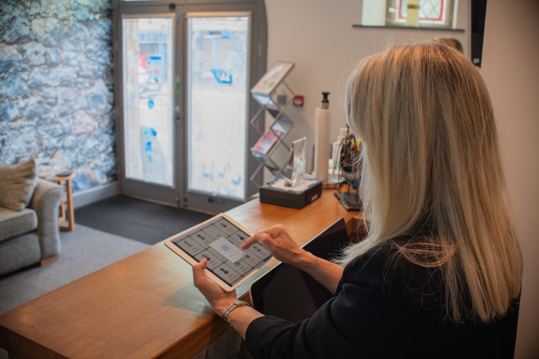 Receptionist at a front desk using a tablet to check in an arriving visitor